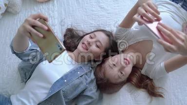 两个漂亮的亚洲朋友正在床上玩<strong>手机</strong>，<strong>消费</strong>技术的概念正在一个